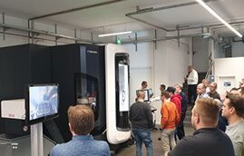 Besucher verfolgen eine Vorführung an einer CNC-Bearbeitungsmaschine beim DELMIA-Machining-Event